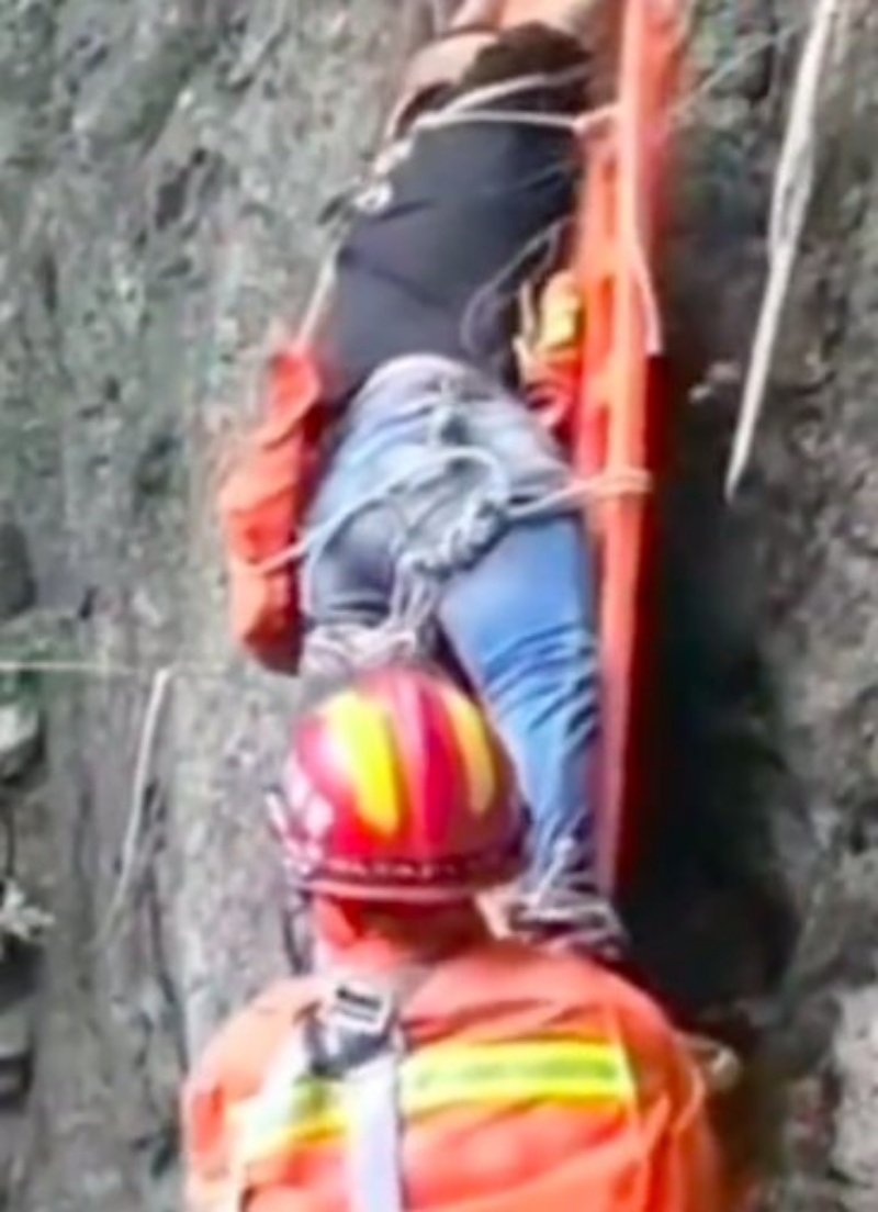 救援人员用担架将男子救下山。网图