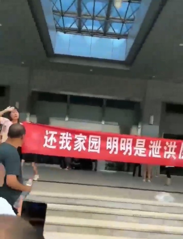 一批村民到政府大樓抗議在現場高舉紅色橫幅布條。網圖