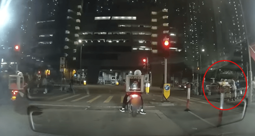 Pizza Hut 哥哥驾驶的电自行车停在红灯前，此时一名婆婆推着一部手推车，上面推起一叠叠高过她的纸皮。网片截图
