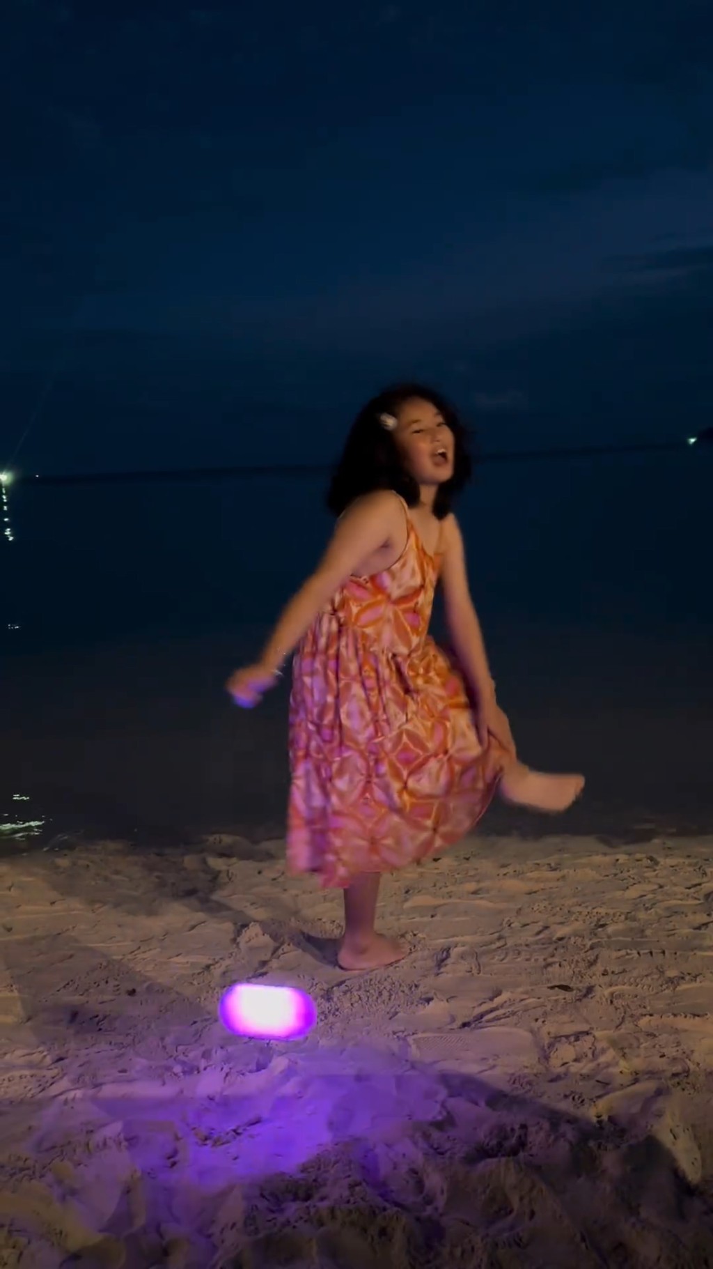 「梁浸浸」晚上在沙灘玩「抛彩球」時，不小心掟中了左腳，她立即轉身向媽咪撒嬌。