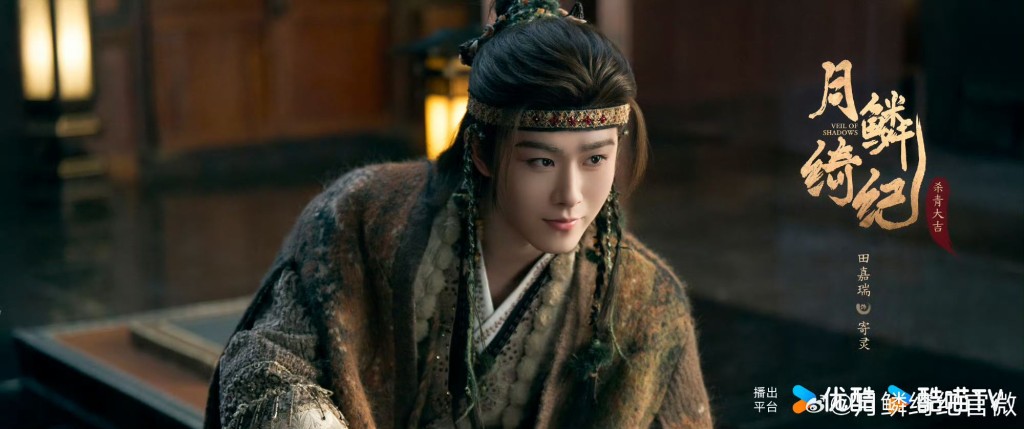 田嘉瑞飾演寄靈。｜田嘉瑞身穿深棕色與草綠色交織的粗花呢質感古裝，頭戴深紅色髮帶，髮絲間綴有綠色串珠，眼神帶著一絲玩世不恭與神祕感。