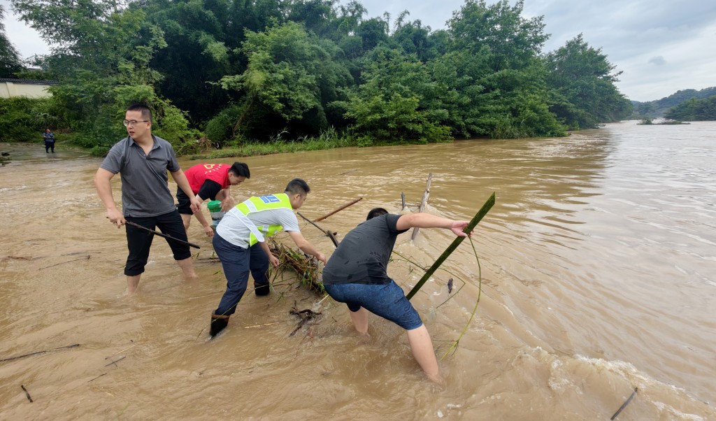 在廣西柳州市融安縣大將鎮大將社區逢村屯，黨員幹部冒雨清理大橋上的雜物。 新華社