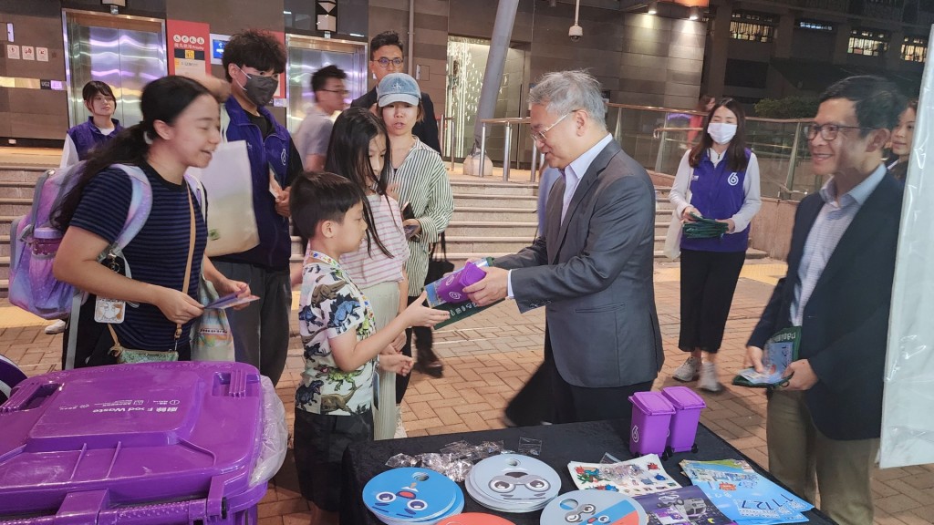 徐浩光（右2）和鄭健（右1）向市民派發紀念品，鼓勵他們積極參與廚餘回收，實踐綠色生活。政府新聞處圖片