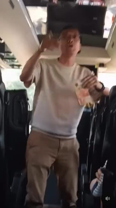 片中所見,李卓興在旅遊巴車頭位置,手持一張1千元「金牛」,帶頭與學生玩「接銀紙遊戲」。 片中所見,李卓興在旅遊巴車頭位置,手持一張1千元「金牛」,帶頭與學生玩「接銀紙遊戲」。