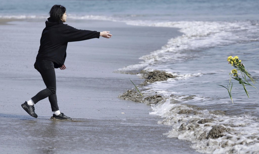 一名婦人將鮮花放在磐城市海邊，悼念311大地震死難者。 美聯社
