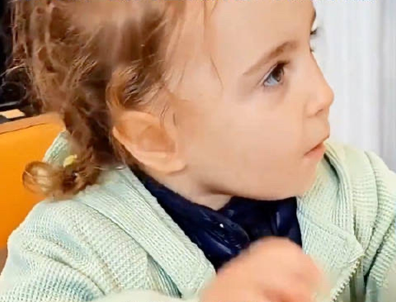 女童有著亮金色捲髮、藍色眼睛與深邃五官。