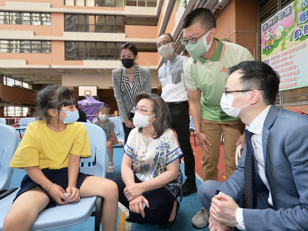 杨何蓓茵（前排中）与一名刚完成接种新冠疫苗的学生（前排左）交谈。
