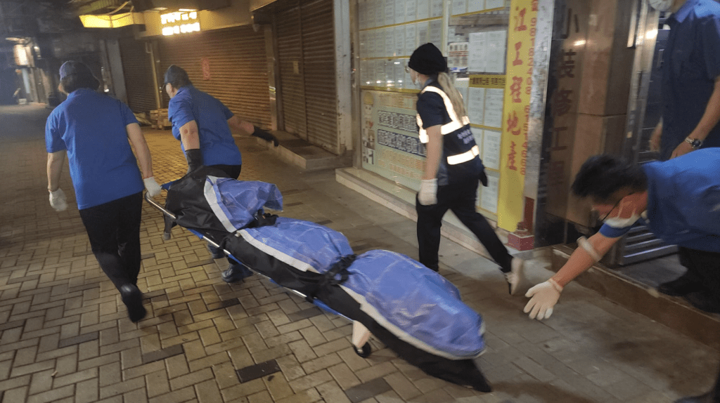 仵工从单位内舁走两具遗体。