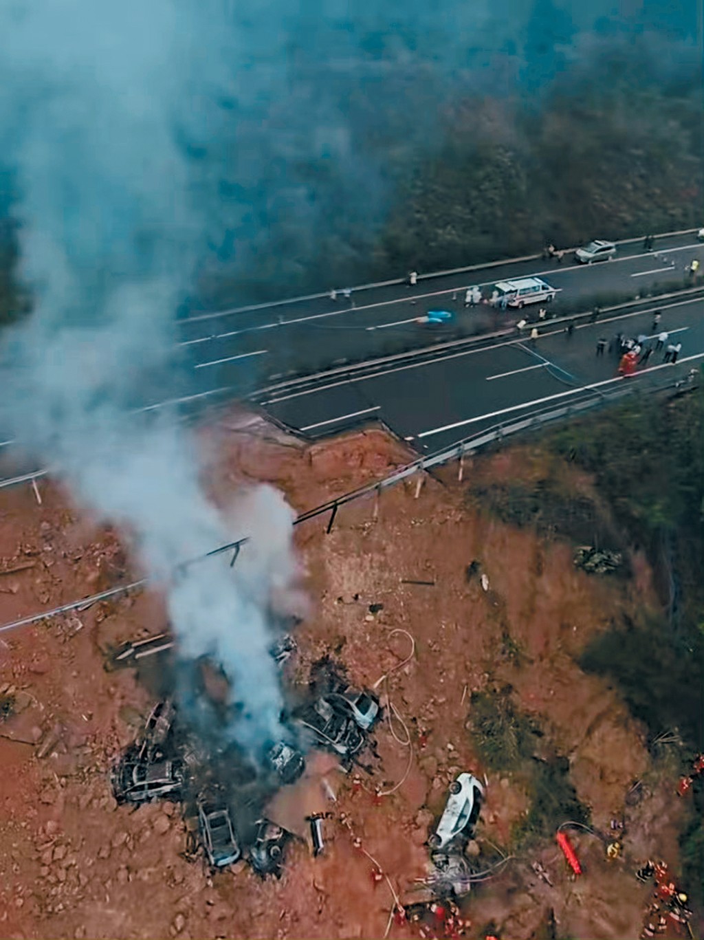 公路塌陷後，多輛汽車滑下山坡，起火爆炸。