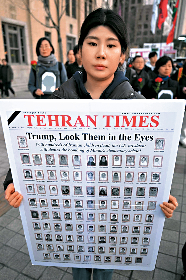 南韓首爾的示威者抗議美軍空襲伊朗小學，舉着登有死難者相片的《德黑蘭時報》。