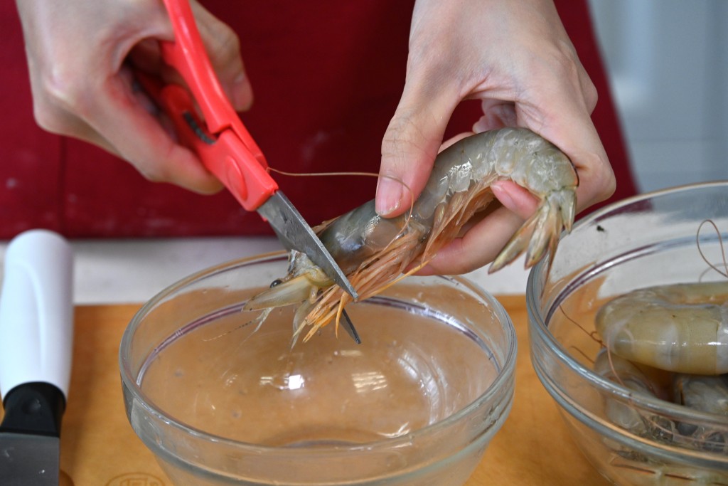 Step 2: 剪去蝦腳、蝦鬚、蝦頭尖位，用牙籤挑去蝦腸，抹乾備用。Trim off the legs, antennae and the sharp part of the head. Use a toothpick to remove the vein. Pat dry and set aside.