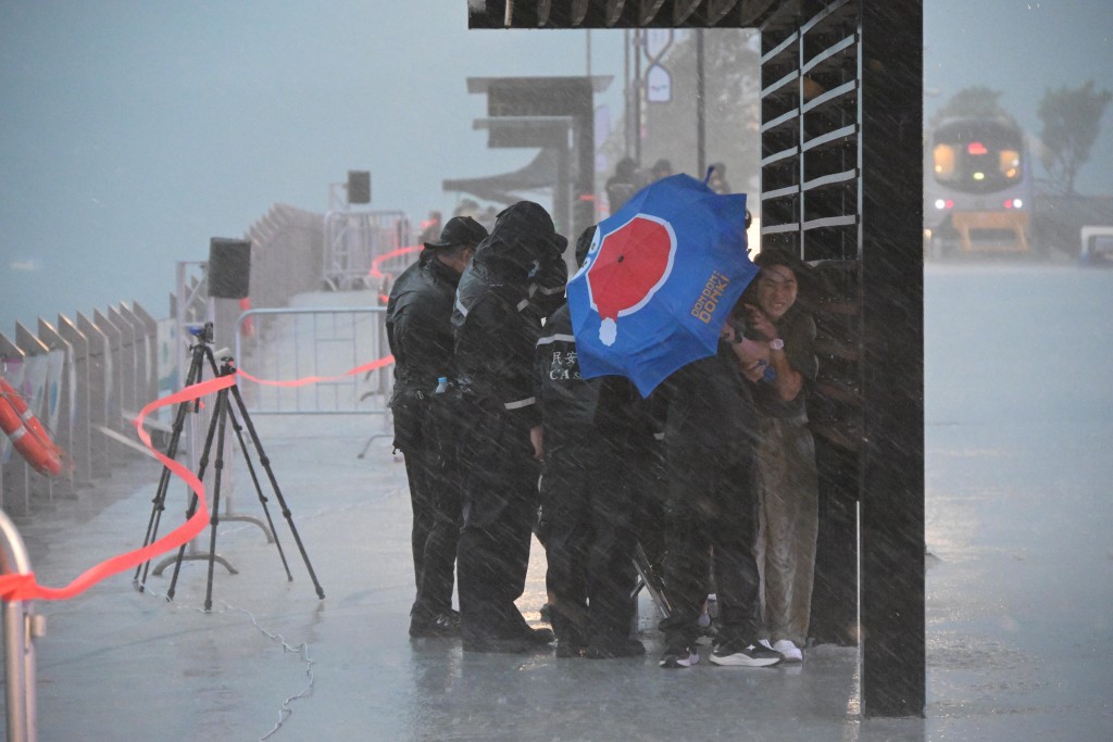 有民安隊協助海邊市民遊客抵擋風雨。蘇正謙攝