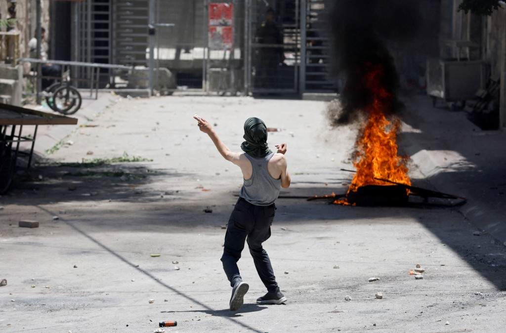 有巴勒斯坦民众在以色列于杰宁的军事行动中掷石还击。(路透社)