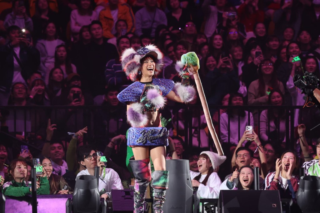 她拿起該粉絲手中印有她樣子的條狀公仔，大讚非常得意。