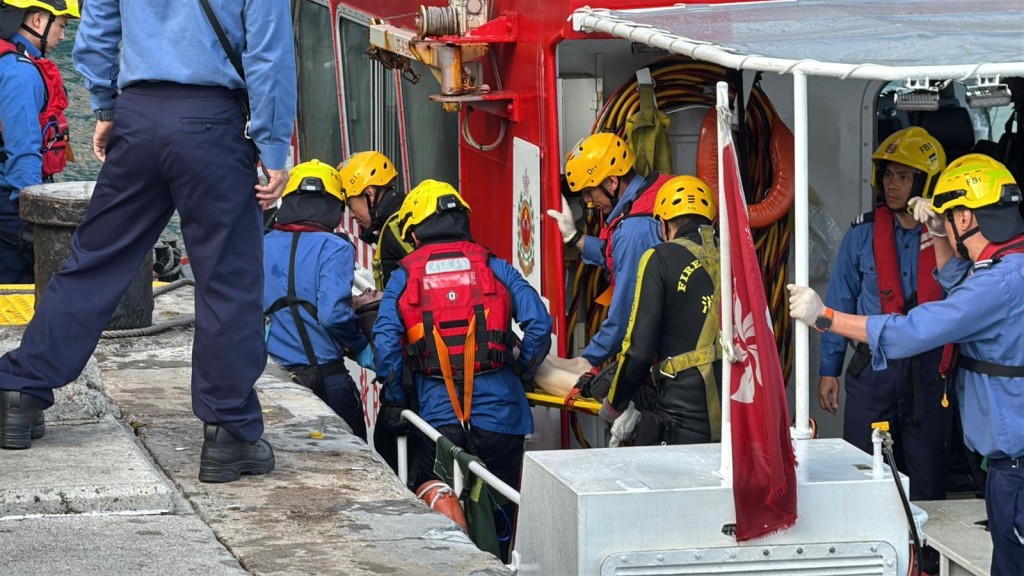 墮海男子被救上船，再靠岸由救護車送院。