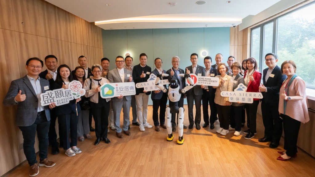 房屋事务委员会主席吴秋北（前排右七）、副主席梁文广（前排右十）和其他议员与政府和房协代表，以及人形运动教练机械人合照。政府新闻处