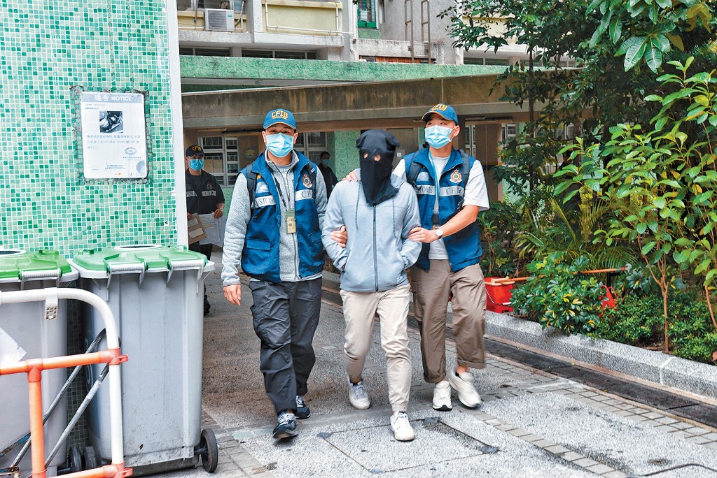 涉嫌洗黑錢罪名被捕男子黑布蒙頭由關員押走。