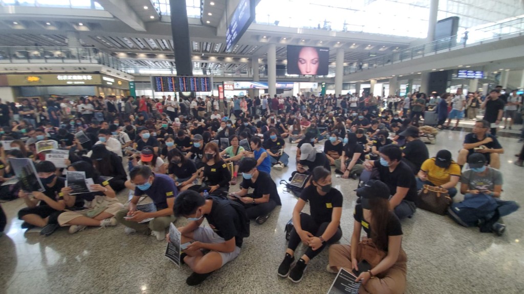 一批黑衣人在接机的抵港大堂静坐。