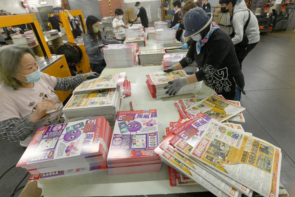 印製工人將「提紙」加進兩份免費報紙內。