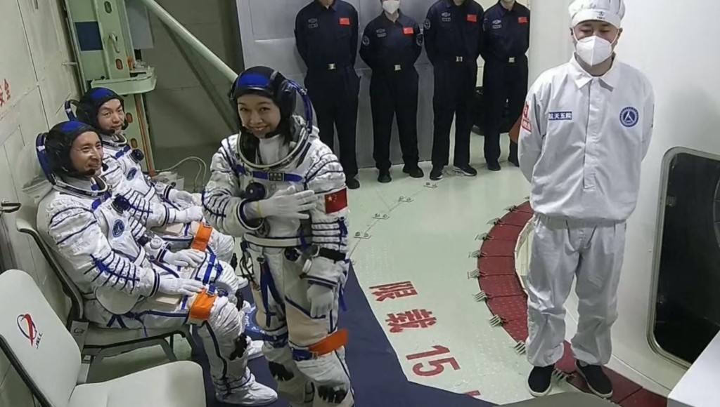 黎家盈轻拍太空衣上的国旗。央视截图