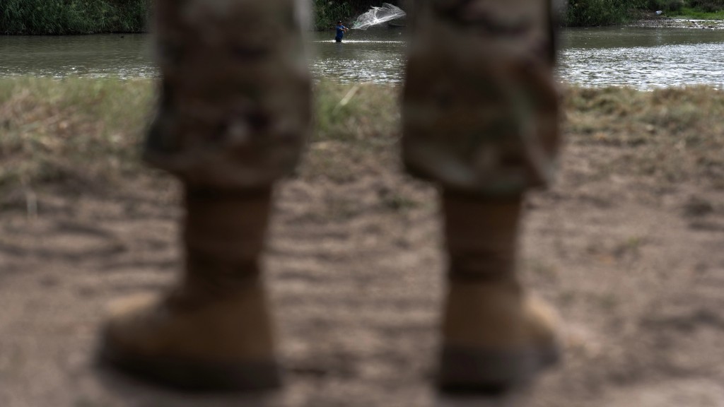 美國陸軍預備役士兵在得州拉雷多岸邊注視一名捕魚的男子。  美聯社 美國陸軍預備役士兵在得州拉雷多岸邊注視一名捕魚的男子。  美聯社