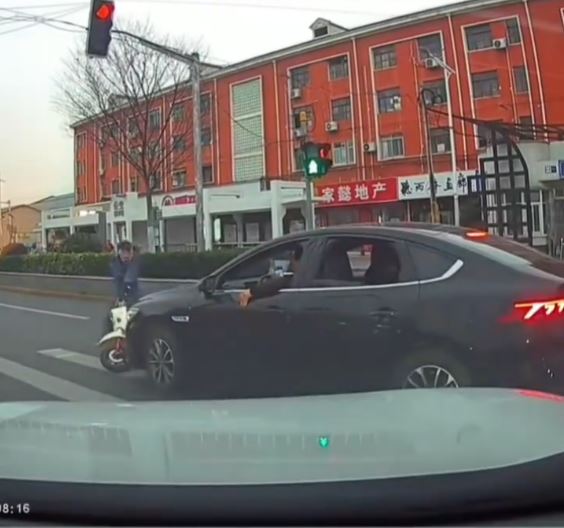 黑色车司机不满女事主停车让路人，举中指挑衅，却撞到一名骑电动车的大叔。