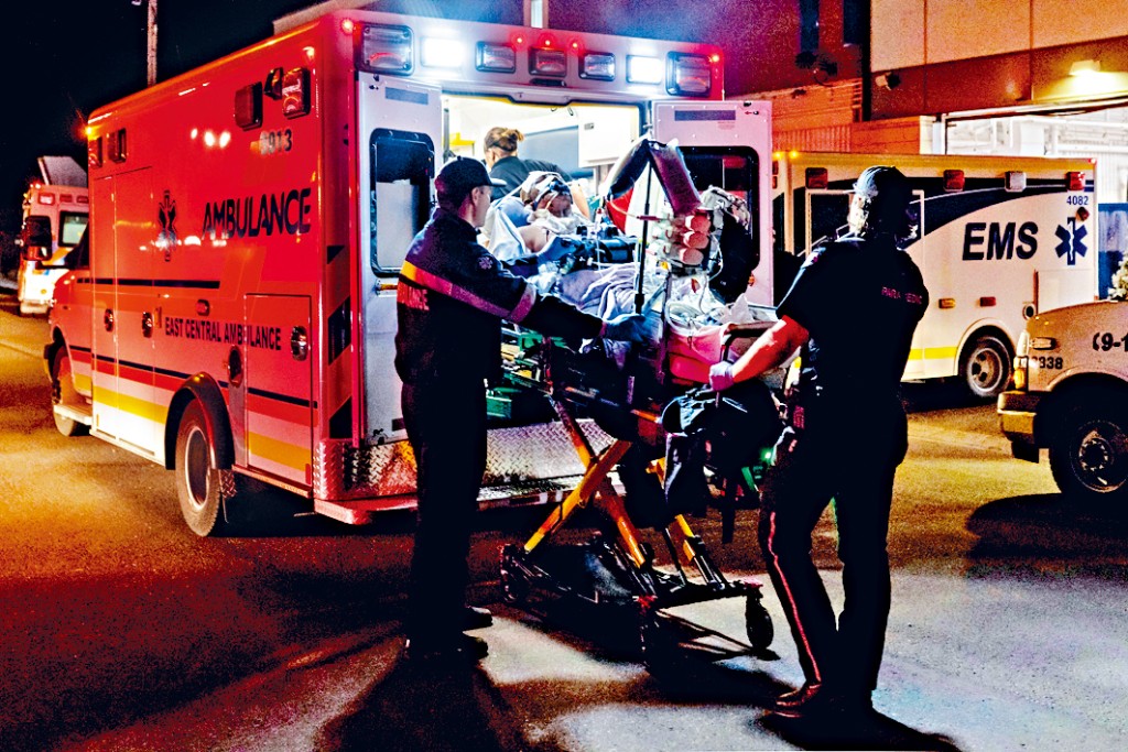 韋恩賴特基地發生火災，醫護人員把一名受傷軍人抬上救護車。