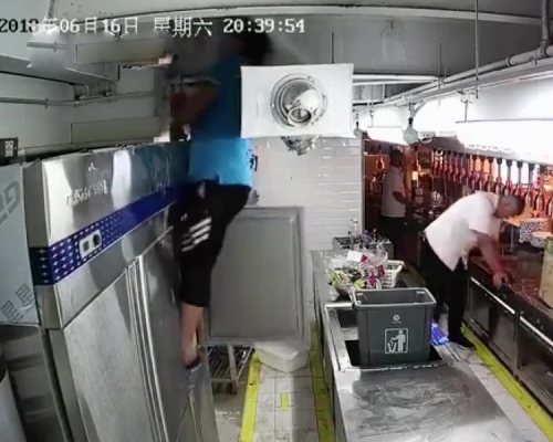 閉路電視曝光後可見，該名正維修雪櫃的電工，懷疑誤觸電源，全身硬直卡在雪櫃與通風管之間。（網圖）