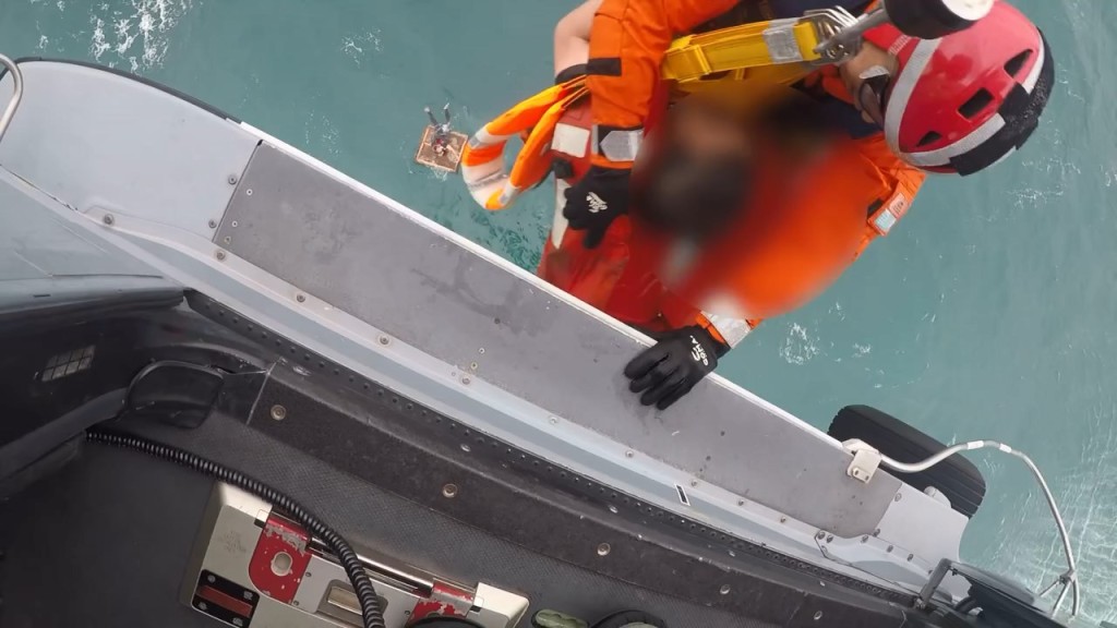 飞行服务队人员冒着狂风将两名被困海中央的船员救起。