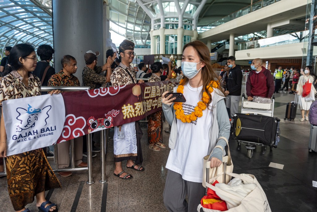 中國遊客佩戴歡迎花環走出巴厘島伍拉萊國際機場。新華社
