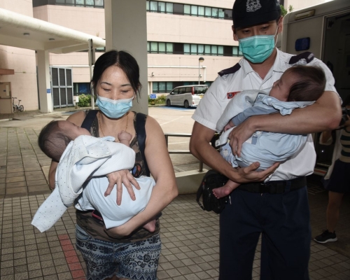 孿生男嬰昨日分別由祖母(左)及男警手抱送院檢驗。