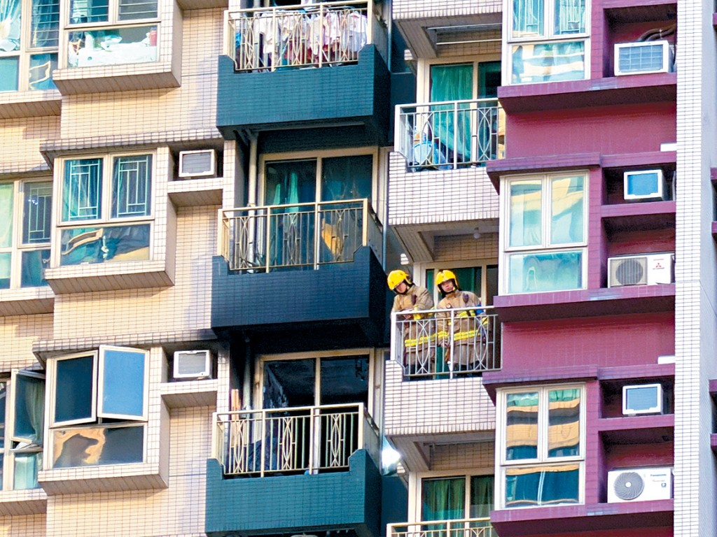 消防員撲滅大火後，在單位內進行調查。 