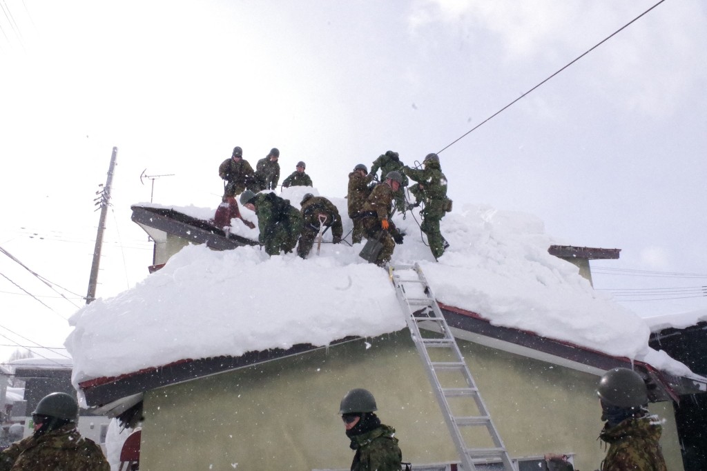日本自衛隊出動助居民清理屋頂積雪。法新社