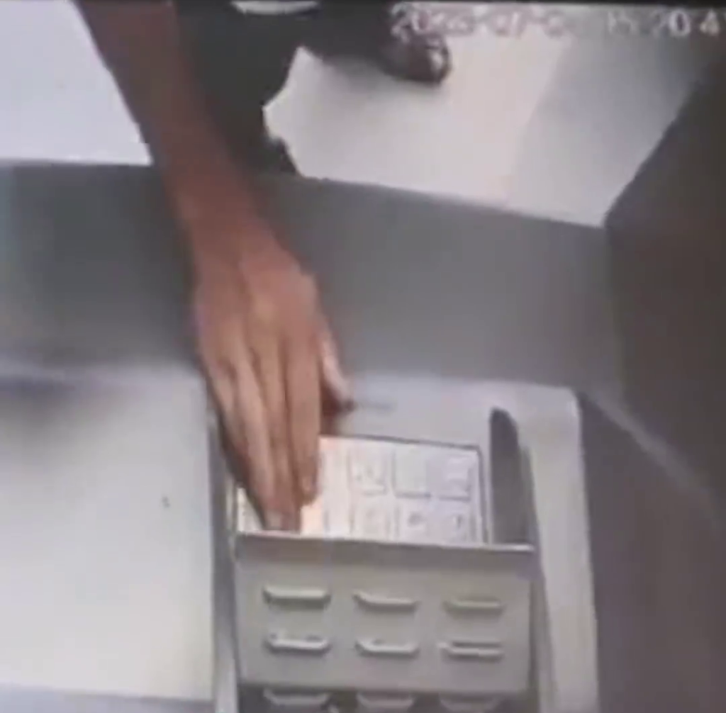闭路电视拍下男子将一叠「阴司纸」放入自动柜员机后，在旁边正常的ATM上查看馀额。