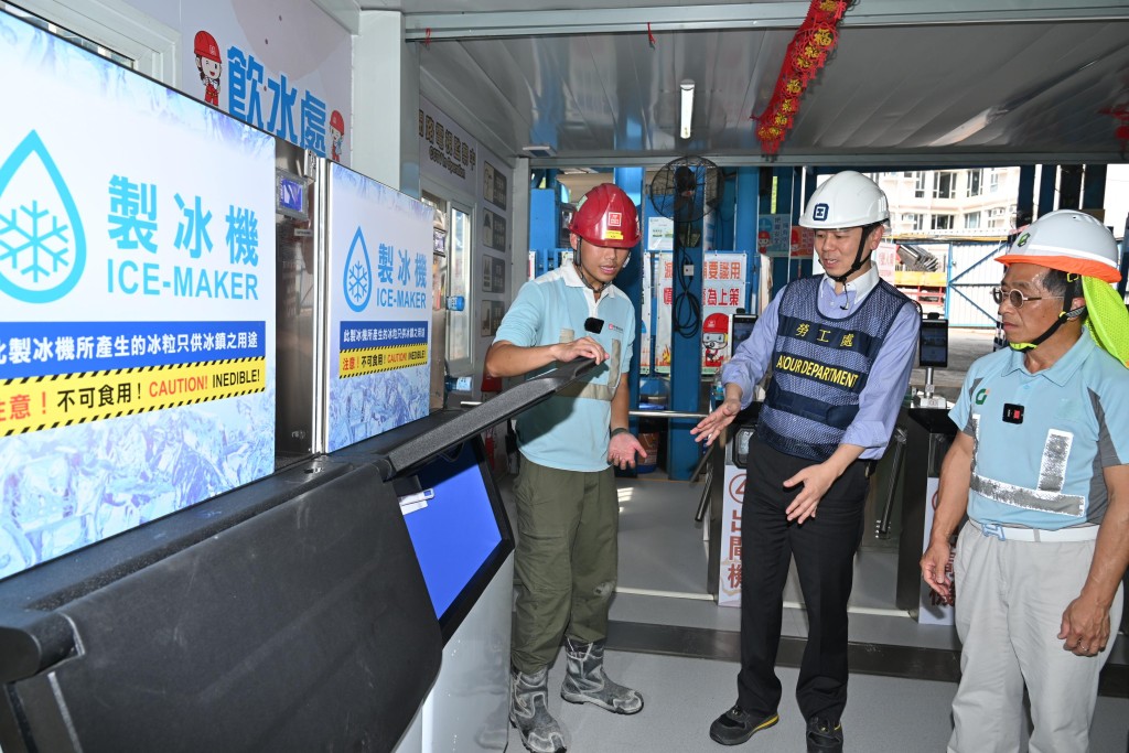 署理勞工處處長馮浩賢（中）和建造業議會主席何安誠（右一）參觀地盤設置的製冰機。 政府新聞處圖片