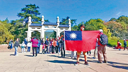 ■杨翰杰在中山陵前手举青天白日旗拍照留念。