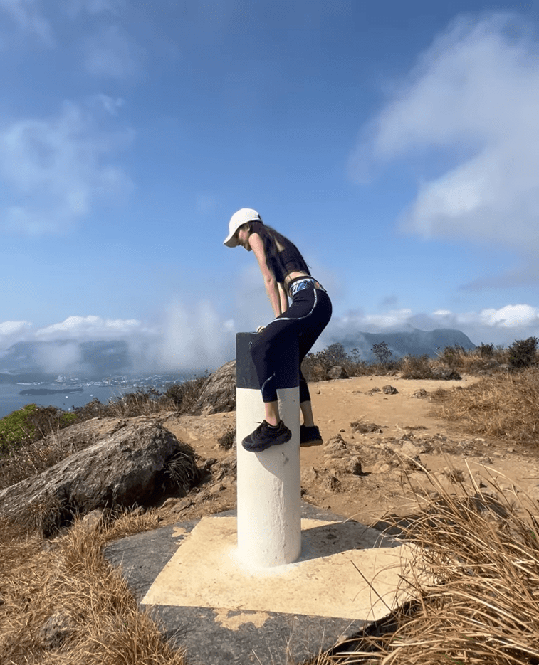 陈凯琳登上山顶时，成功一跃而上坐在山顶标竿的圆柱。
