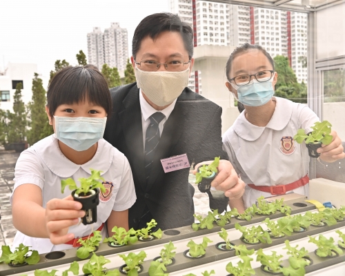 薛永恒在保良局王赐豪（田心谷）小学与介绍物联网「空中花园」项目的学生合照。政府新闻处图片