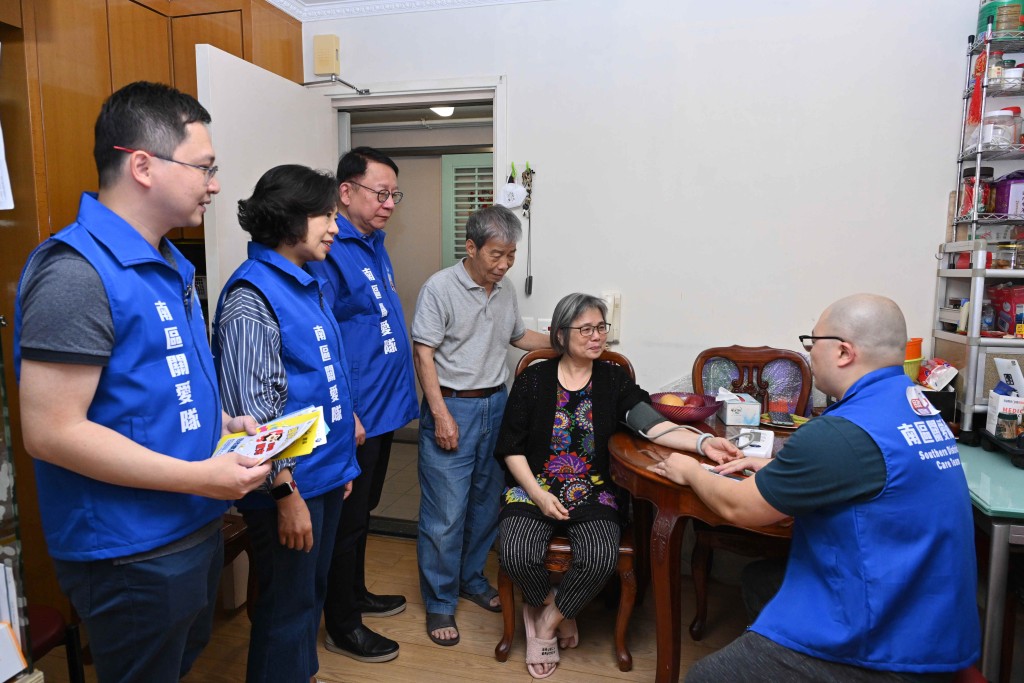 陳國基在麥美娟和南區民政專員鄭港涌（左一）陪同下，在典禮前探訪南區雙老家庭，並為他們量度血壓。（政府新聞處）
