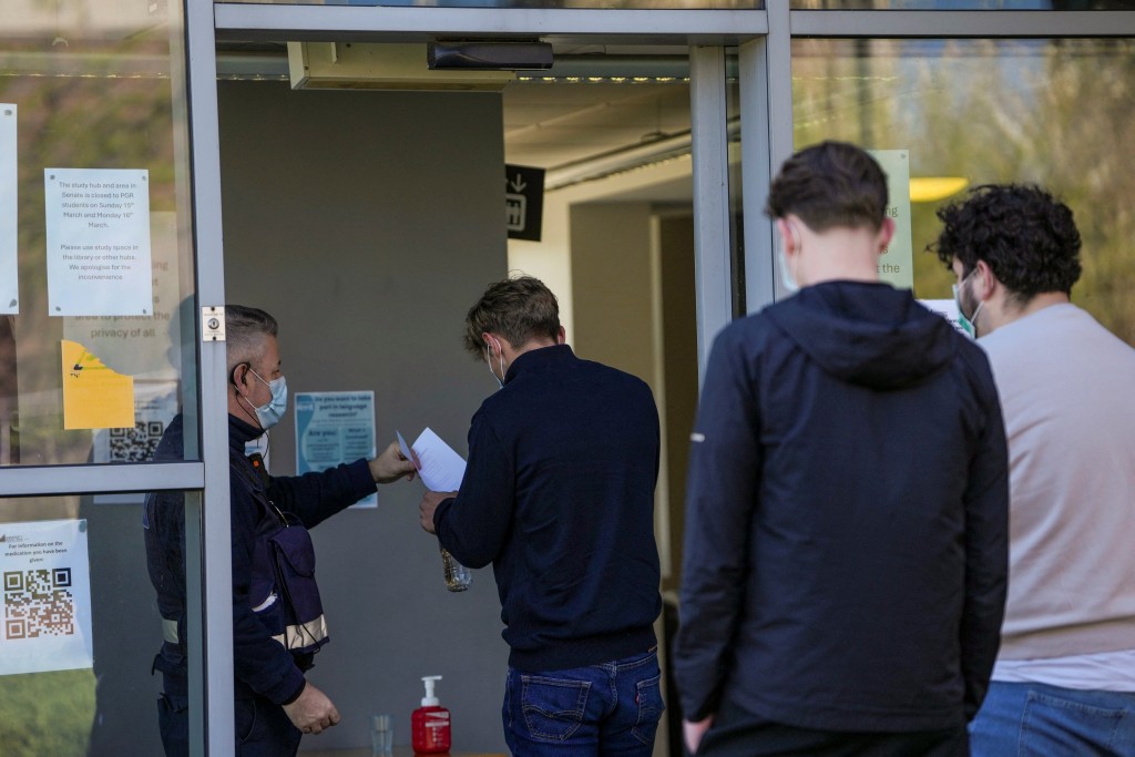 在英格兰东南部一校园内,人们戴著口罩在临时医疗中心排队领取抗生素。(法新社) 在英格兰东南部一校园内,人们戴著口罩在临时医疗中心排队领取抗生素。(法新社)