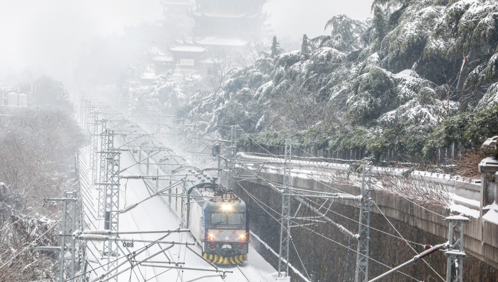 湖北武漢降雪天氣持續，內燃機車列車雪中從武漢黃鶴樓旁駛過。