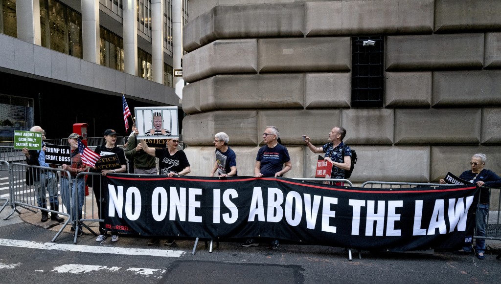 示威者聚集在特朗普抵達紐約作證的車隊之前，拉橫額抗議。AP