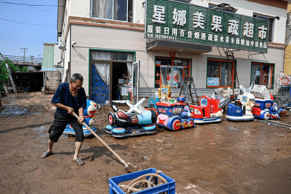 北京暴雨災情，民眾清理地上淤泥。 法新社