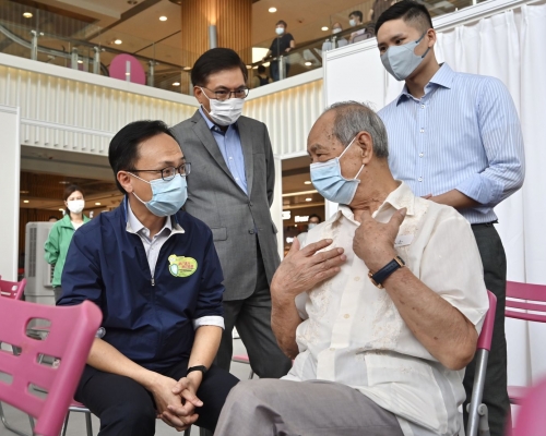 聶德權（前排左）與一名參與疫苗接種活動的長者交談。政府新聞處圖片
