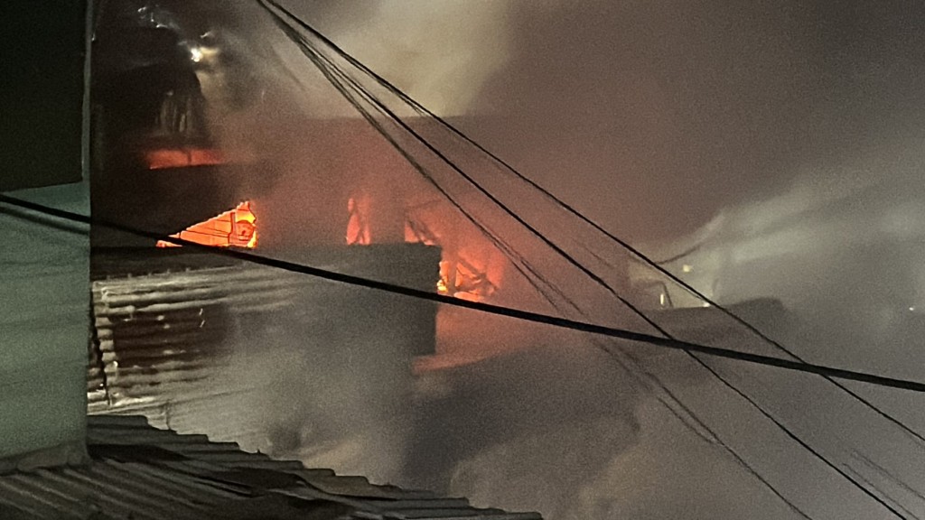 锦公路旁的光板田村附近山坡起火，随后邻近2间铁皮屋冒出火舌，被烧至通顶。李家杰摄