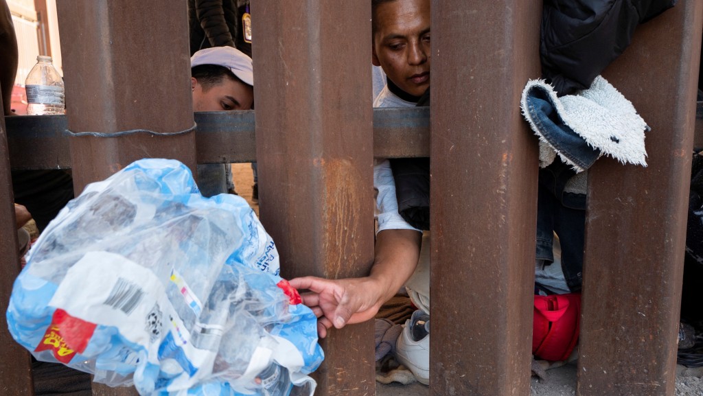 在墨西哥聖路易斯里奧科羅拉多，「第42條」 解除前，一些移民透過美墨邊境圍牆伸手取水。 路透社