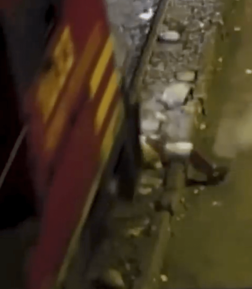 從畫面角度顯示，火車頭已掩蓋了他的臉，當大家都以為他將一命嗚呼。社交平台影片截圖 / International Agency for Journalism AIJES  @aijesinfo
