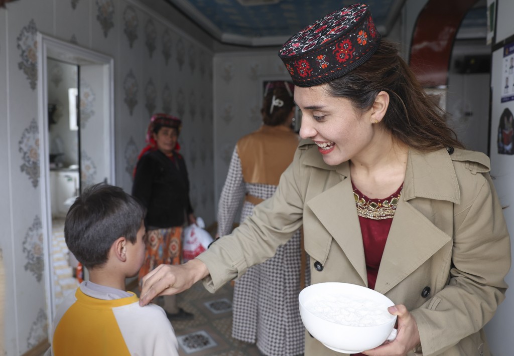 位于新疆塔什库尔干塔吉克斯坦自治县瓦恰乡夏布孜喀拉村的家中，艾尔开牙·多力开（右）向来访宾客右肩撒面粉以示祝福。 新华社