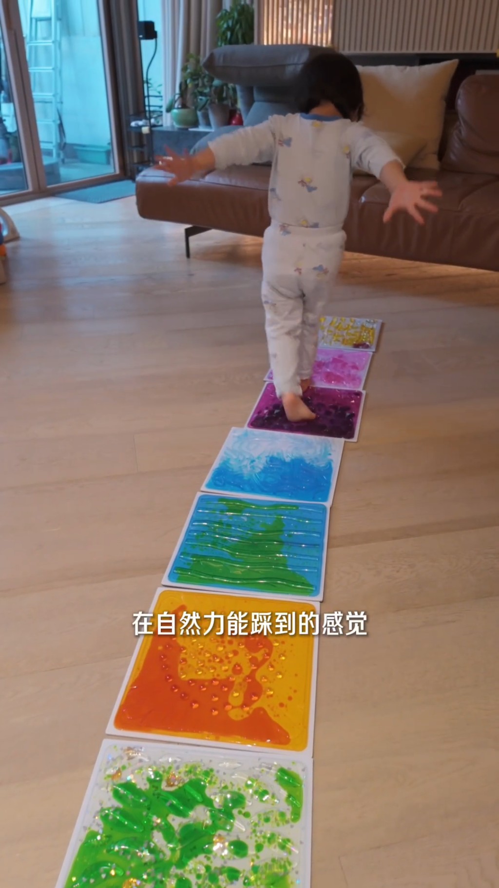 大仔赤腳走在彩色液體地磚上，模擬大自然的觸感。