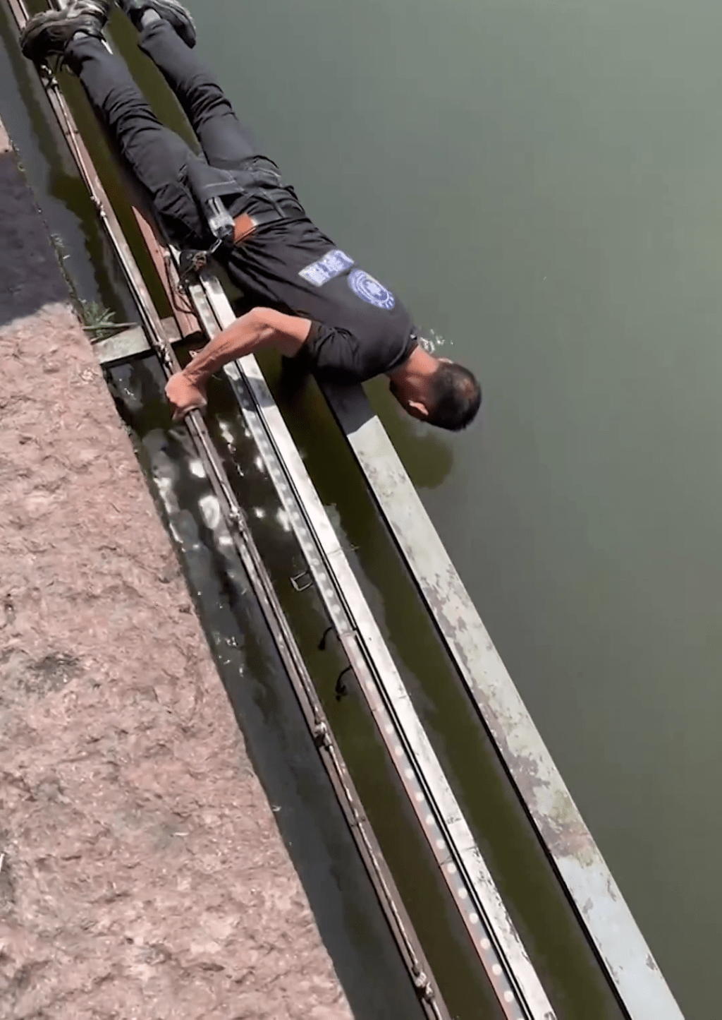 男子在湖边伸手捞手机。